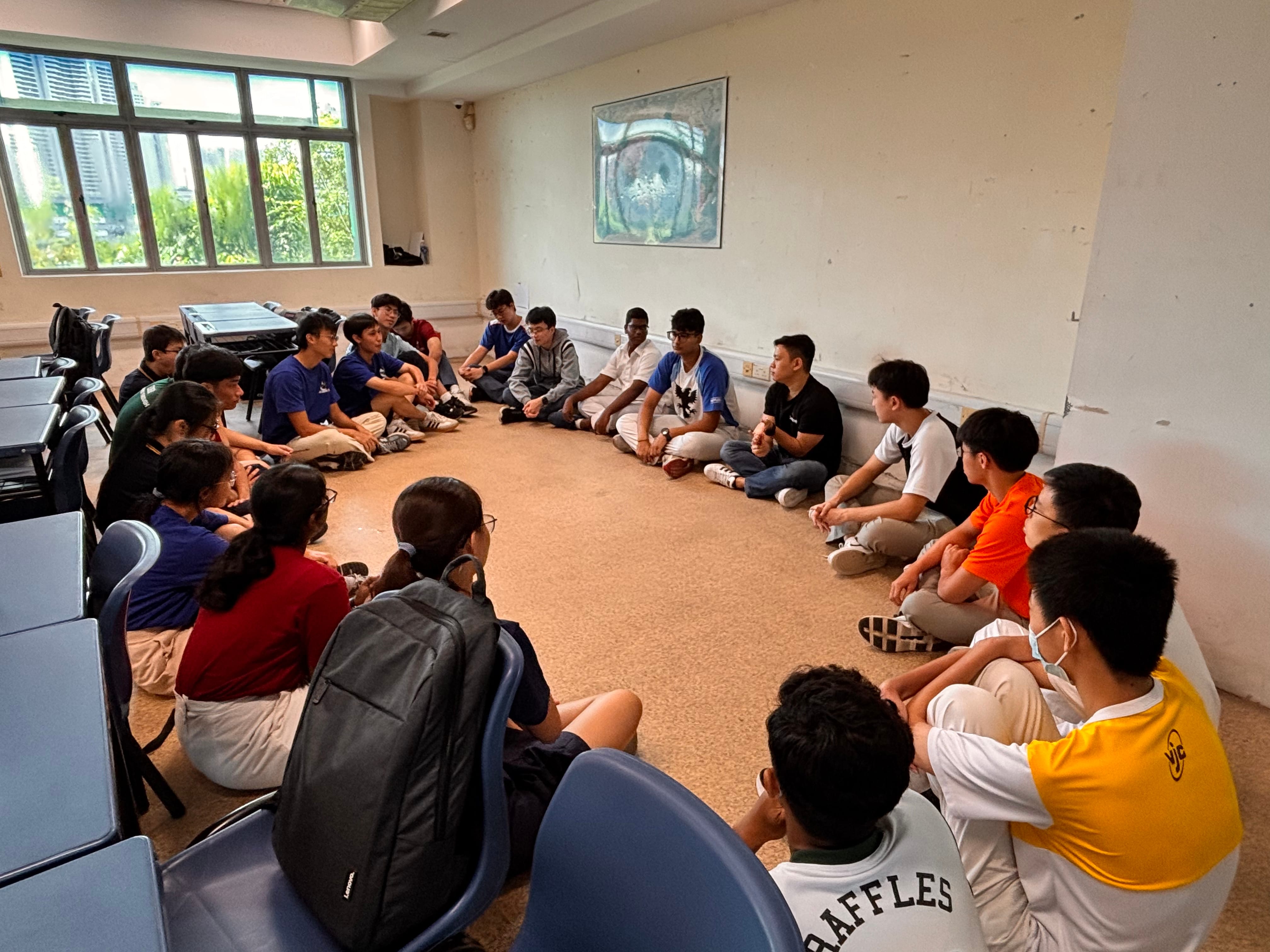 A group of students seated around in a circle for group activity, in a classroom